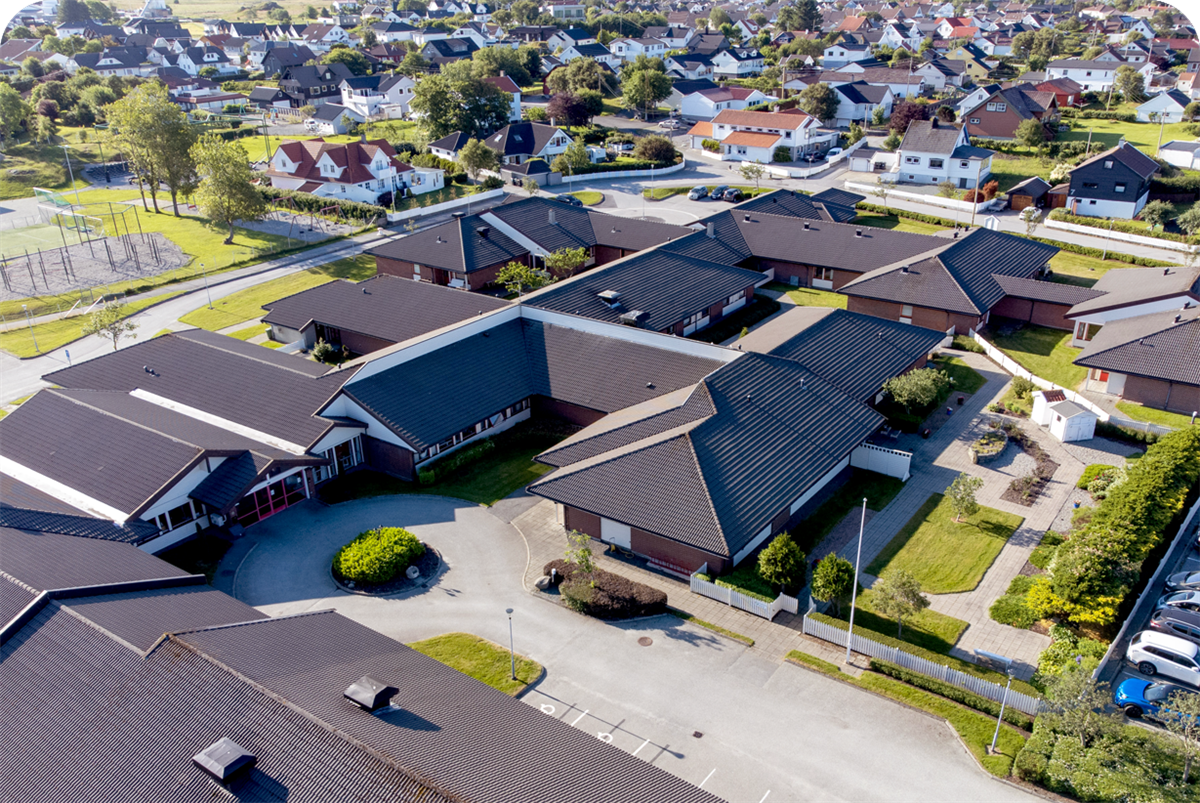 Luftfoto fra Åkra sykehjem som viser hovedbygg og uteområde - Klikk for stort bilde