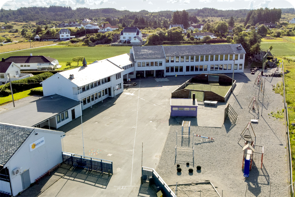 Luftfoto som viser Ferkingstad skole. Hovedbygg og uteområde. - Klikk for stort bilde