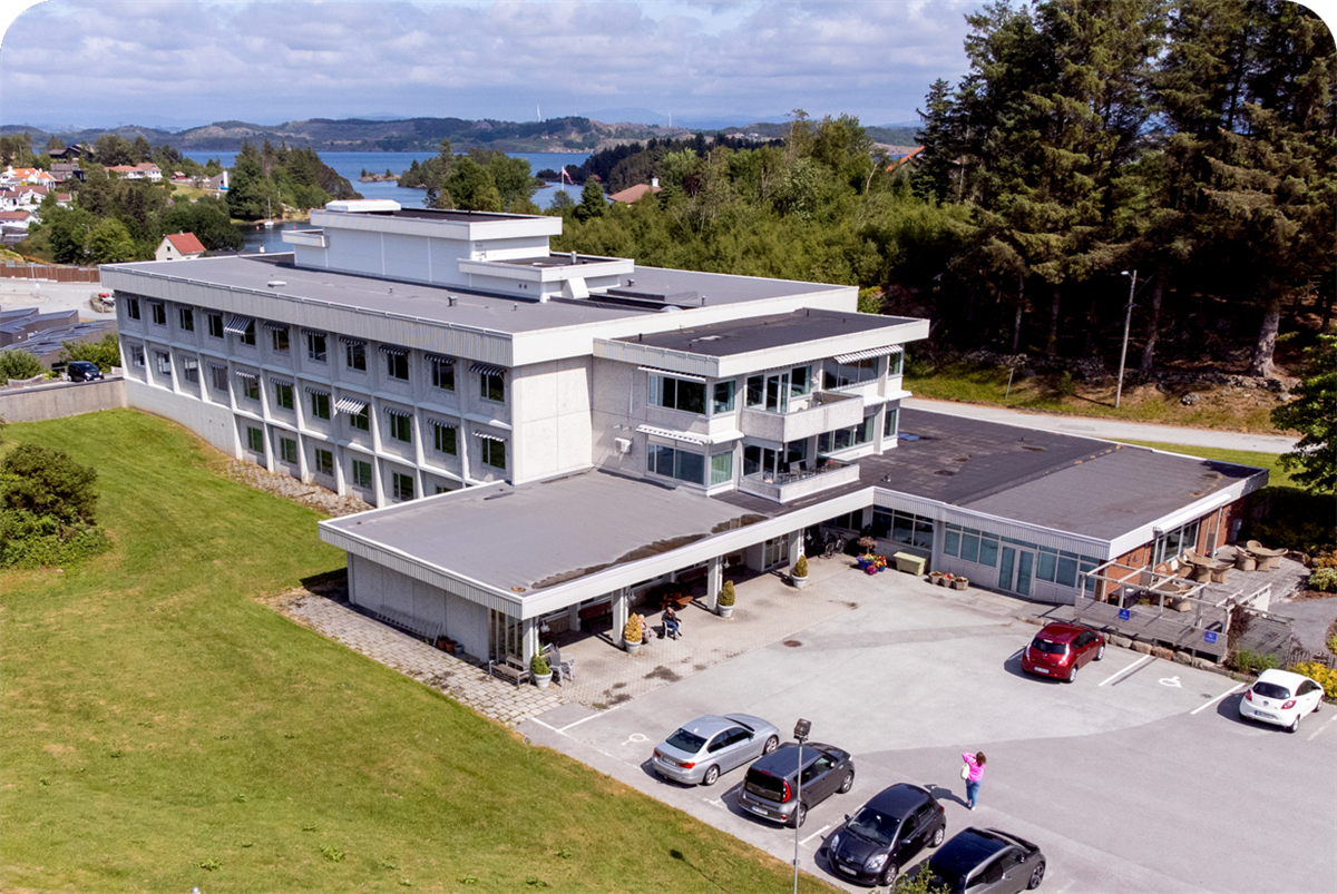 Luftfoto av Kopervik sykehjem som viser hovedbygg og uteområder - Klikk for stort bilde