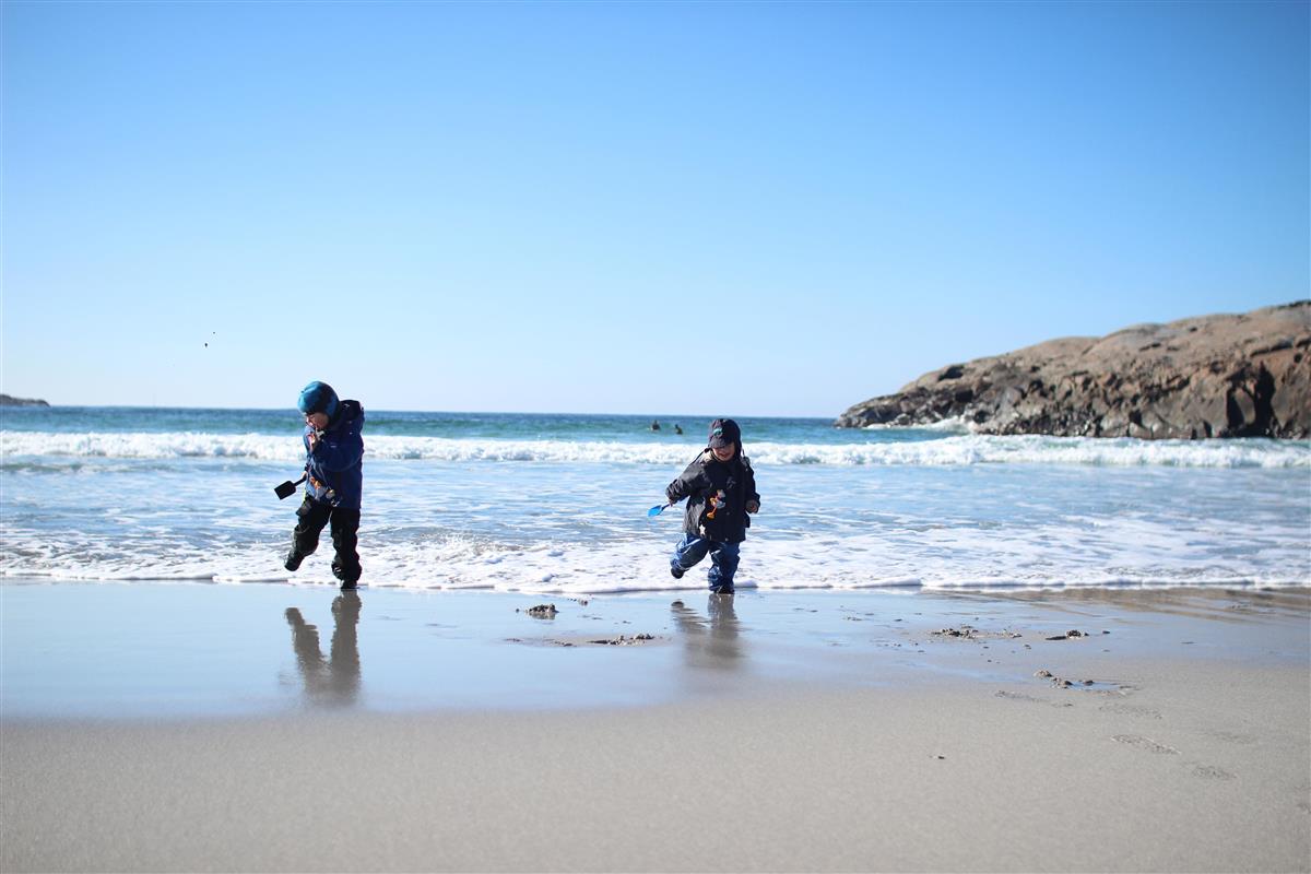 To barn flyr drager på en strand. - Klikk for stort bilde