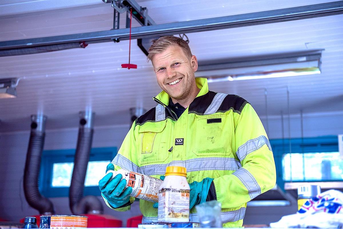 Bilde av en smilende driftsleder som sorterer farlig avfall - Klikk for stort bilde