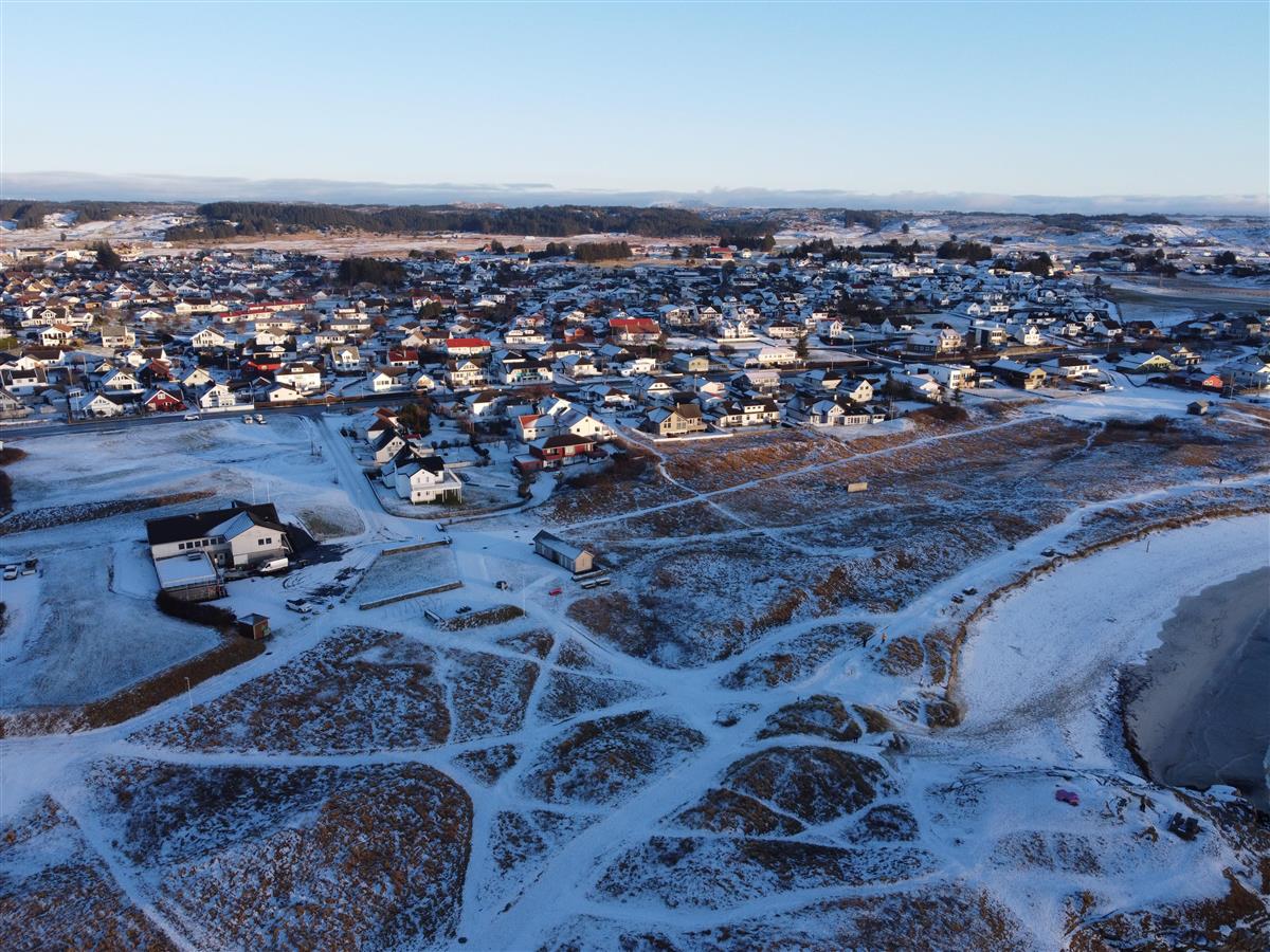 Flybilde av Åkrasanden hvor en ser stiene på kryss og tvers i vegetasjonsbeltet ved stranden - Klikk for stort bilde
