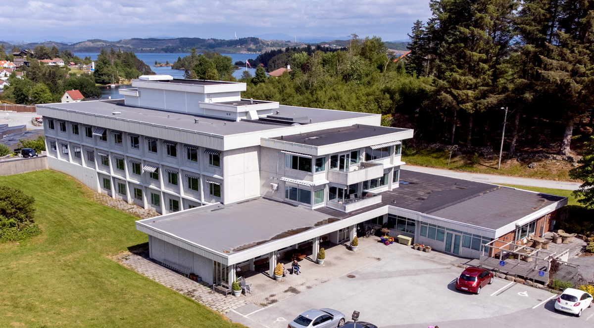 Luftfoto av Kopervik sykehjem som viser hovedbygg og uteområder - Klikk for stort bilde